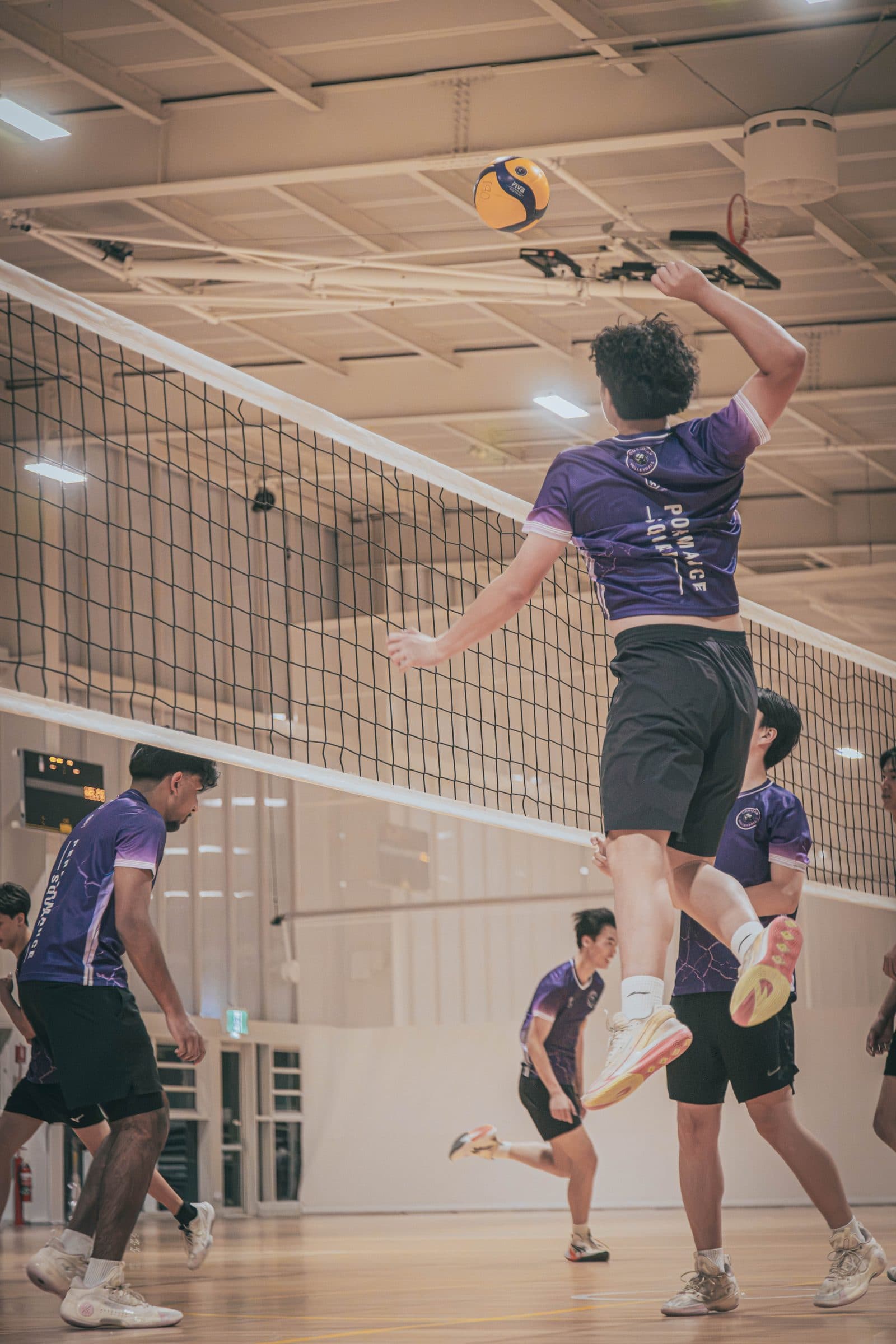 Player in purple Obsidian kit attacking at the net while two teammates block during a West Ryde session