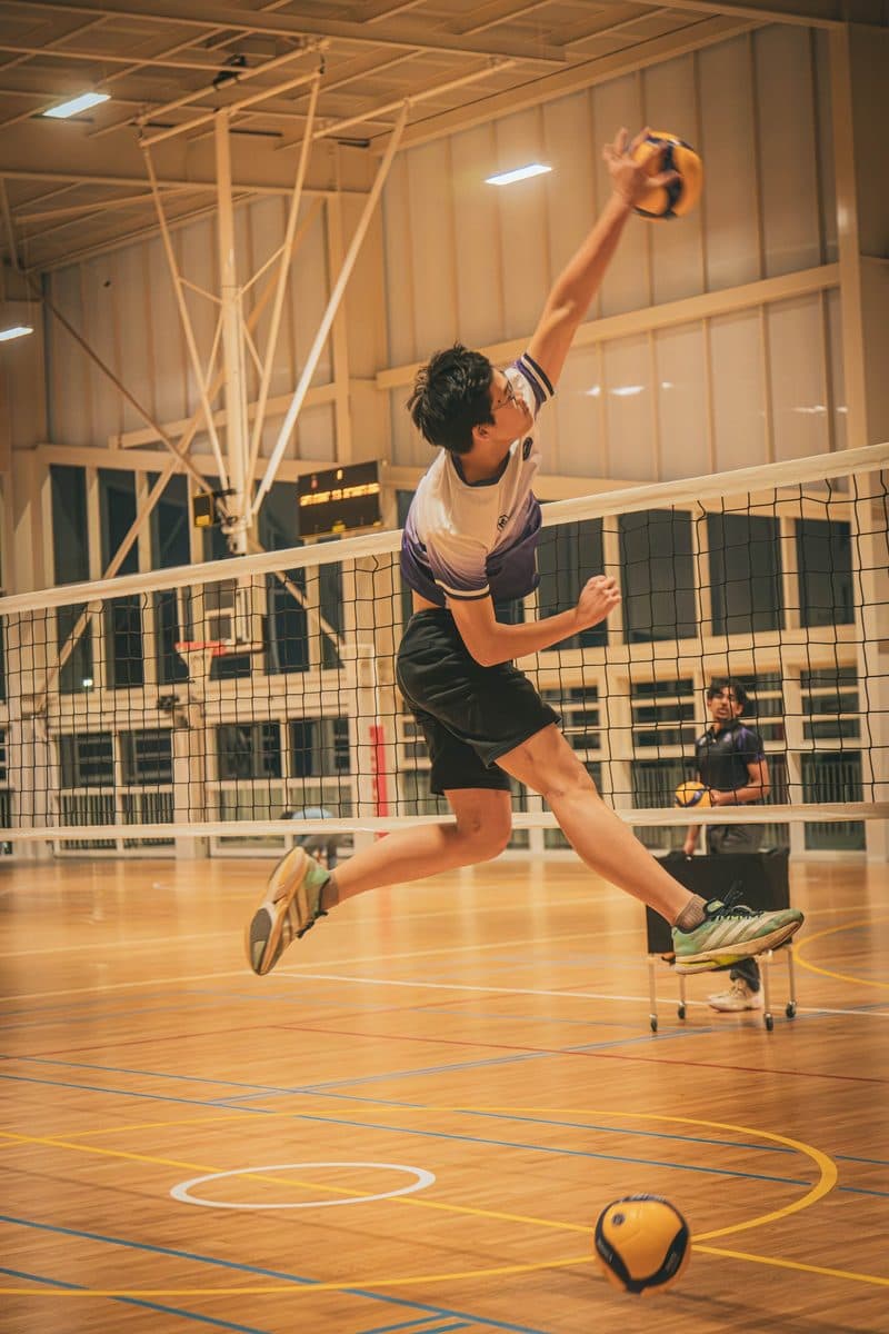 Player in Obsidian jersey leaping to spike at the net inside the Kellyville sports hall