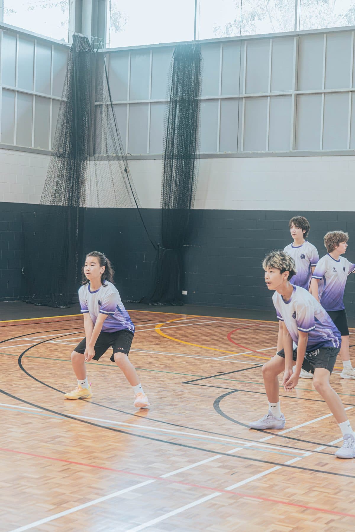 Junior players in Obsidian jerseys in a ready stance on the court at Ryde Aquatic Leisure Centre